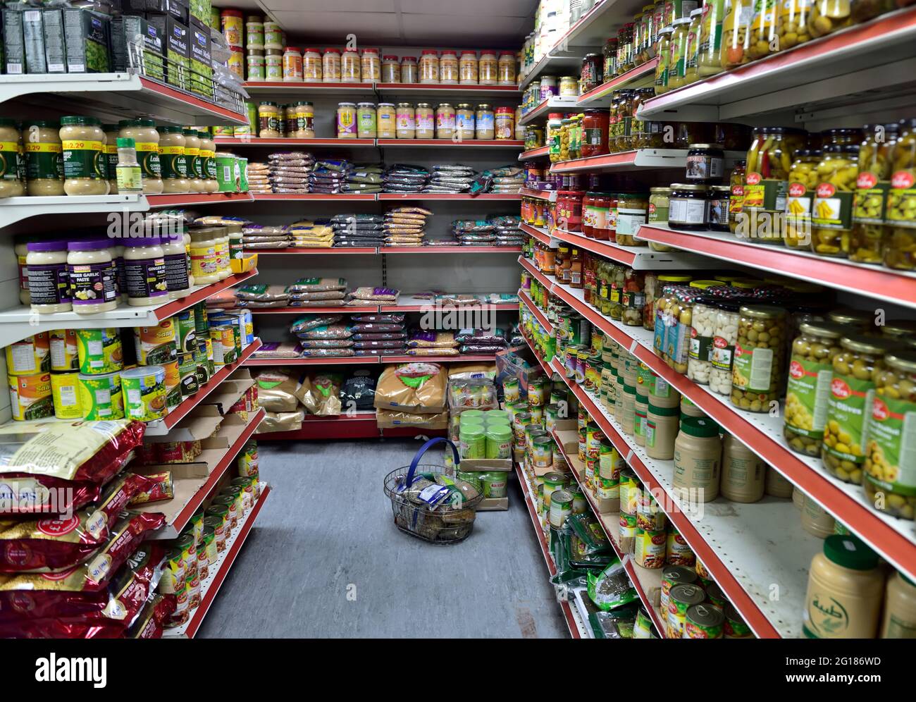 Shelves full of bags of dried pulses, lentils and other with jars and tins of food in small local well stocked corner grocery shop, UK Stock Photo