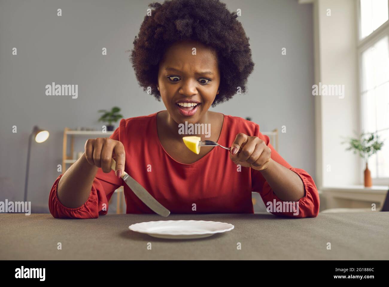 Unhappy angry screaming african american woman on diet looking at piece of apple Stock Photo