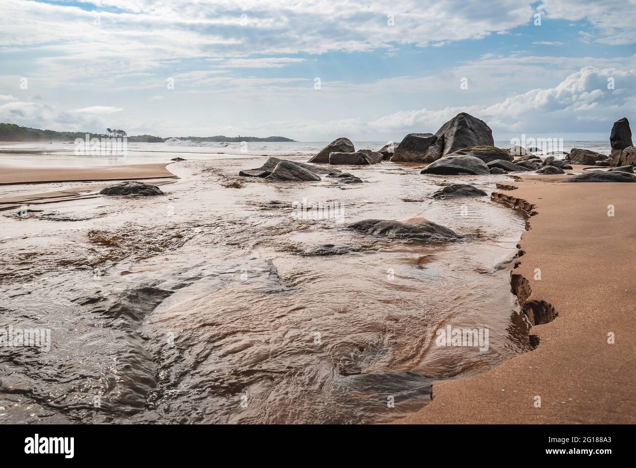 Black dark boulders lying on a beach after the coast in Axim Ghana West Africa Stock Photo