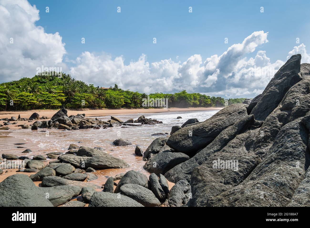 Black dark boulders lying on a beach after the coast in Axim Ghana West Africa Stock Photo