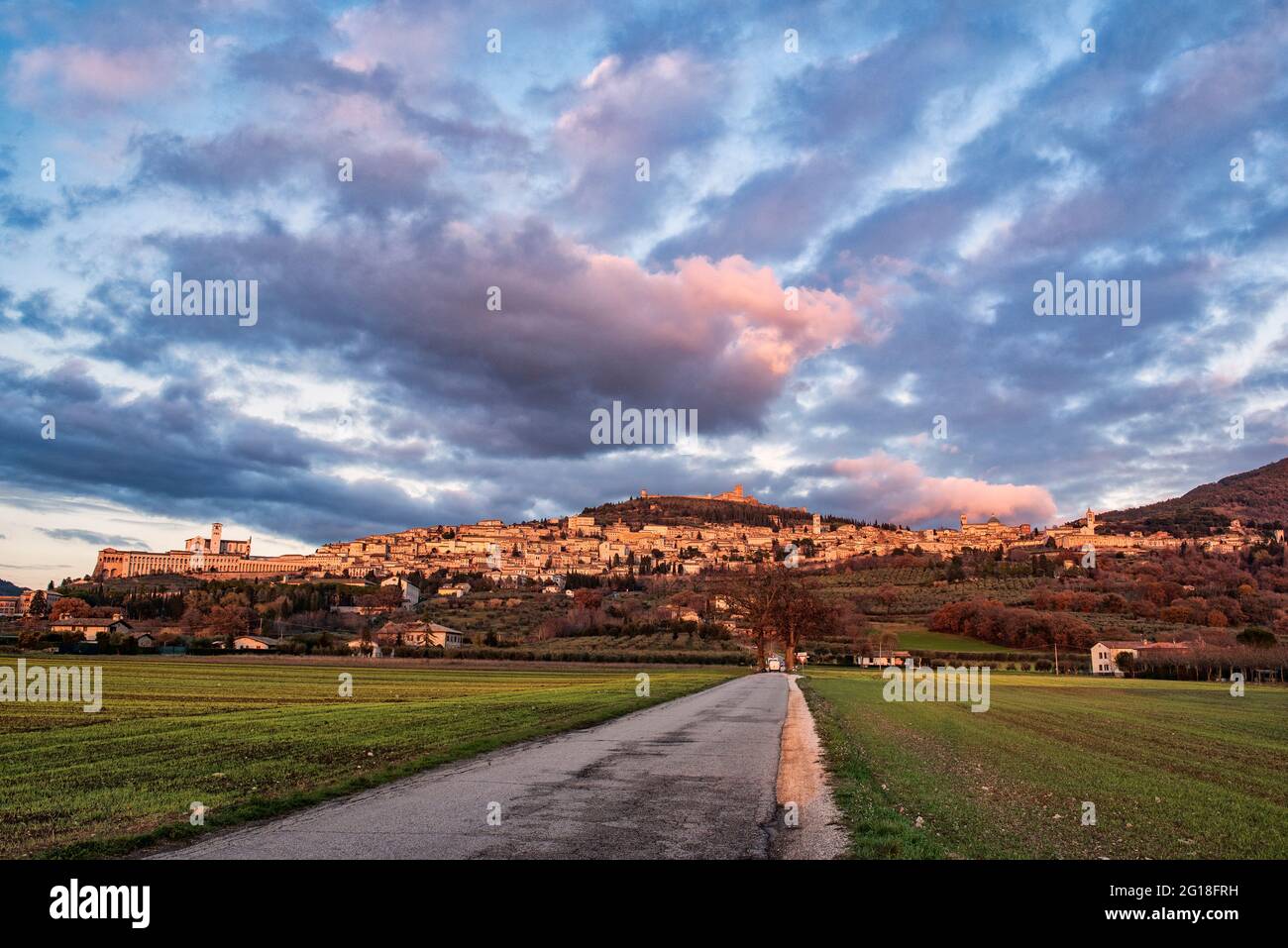 Panorama of Assisi, city of San Francesco, Perugia, Umbria, green heart of Italy. The beautiful sky with clouds and the road in the foreground Stock Photo