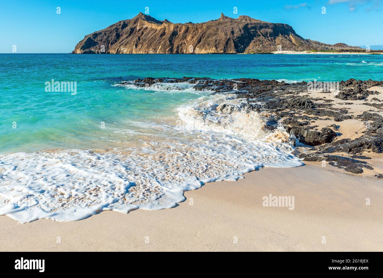 Galapagos beach landscape with strong waves, Stephens Bay with Witch Hill in background, San Cristobal island, Galapagos, Ecuador. Stock Photo