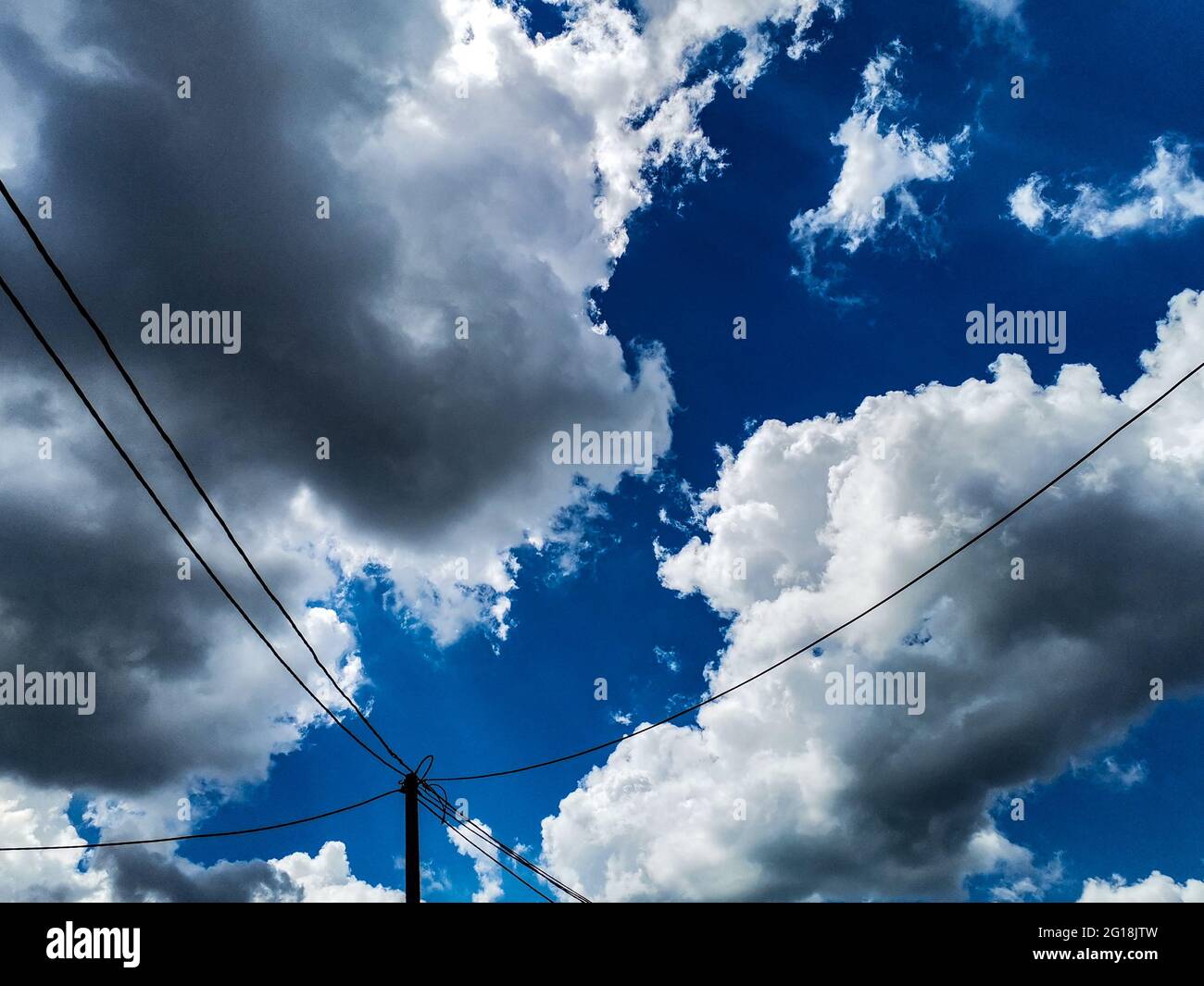 Low angle shot of electrical poles and wires under a blue cloudy sky in ...
