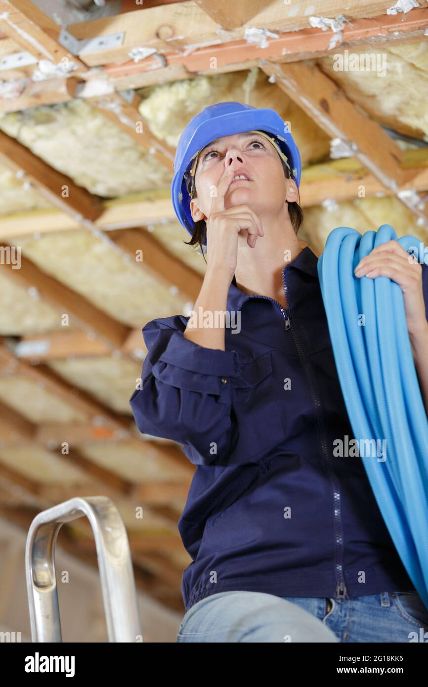 a female plumber working on ceiling Stock Photo