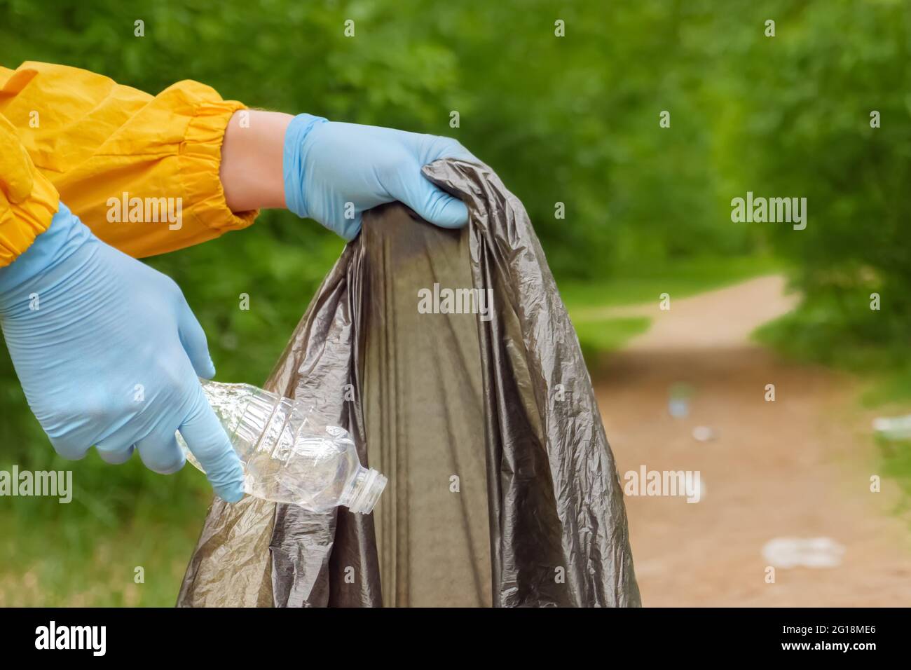 Volunteer hands picks up plastic garbage from grass in park. Volunteer