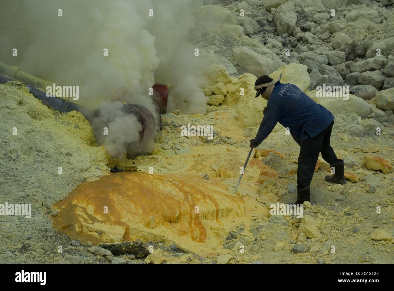 A miner prising out sulphur chunks with a rod inside Kawah Ijen volcano ...