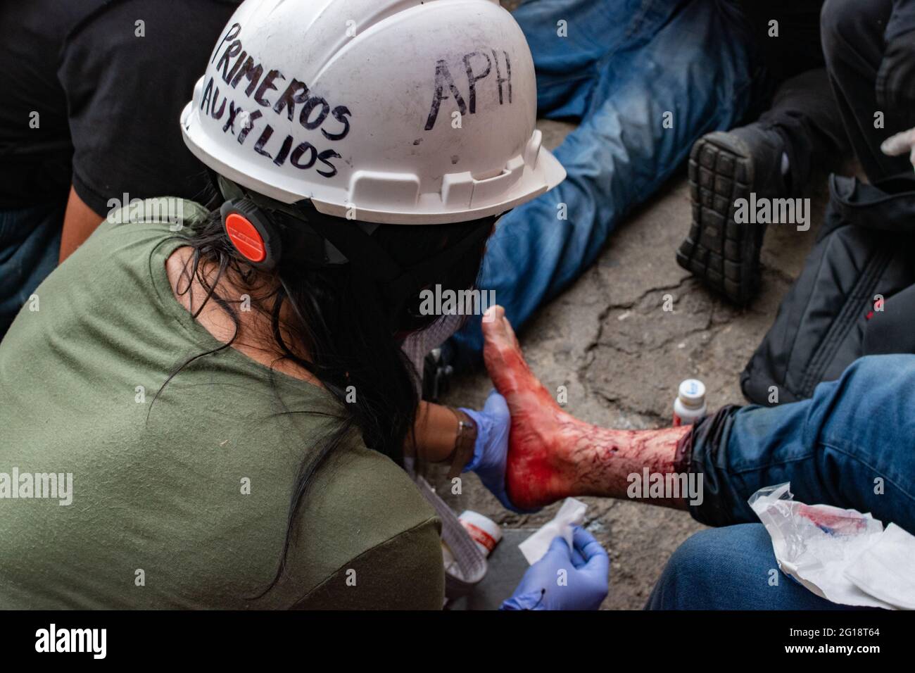 A member of a health brigade assists an injured demonstrator as clashes between demonstrators and Colombia's riot police (ESMAD) erupt in Medellín, Colombia after several weeks of anti-government protest against President Ivan Duque's tax and health reforms and unrest and abuse of authority cases that leave at least 70 dead according to NGOs on June 4, 2021. Stock Photo
