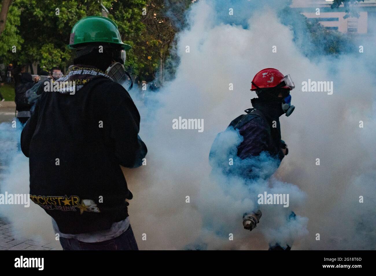 Demonstrators retun and mitigate tear gas as clashes between demonstrators and Colombia's riot police (ESMAD) erupt in Medellín, Colombia after several weeks of anti-government protest against President Ivan Duque's tax and health reforms and unrest and abuse of authority cases that leave at least 70 dead according to NGOs on June 4, 2021. Stock Photo