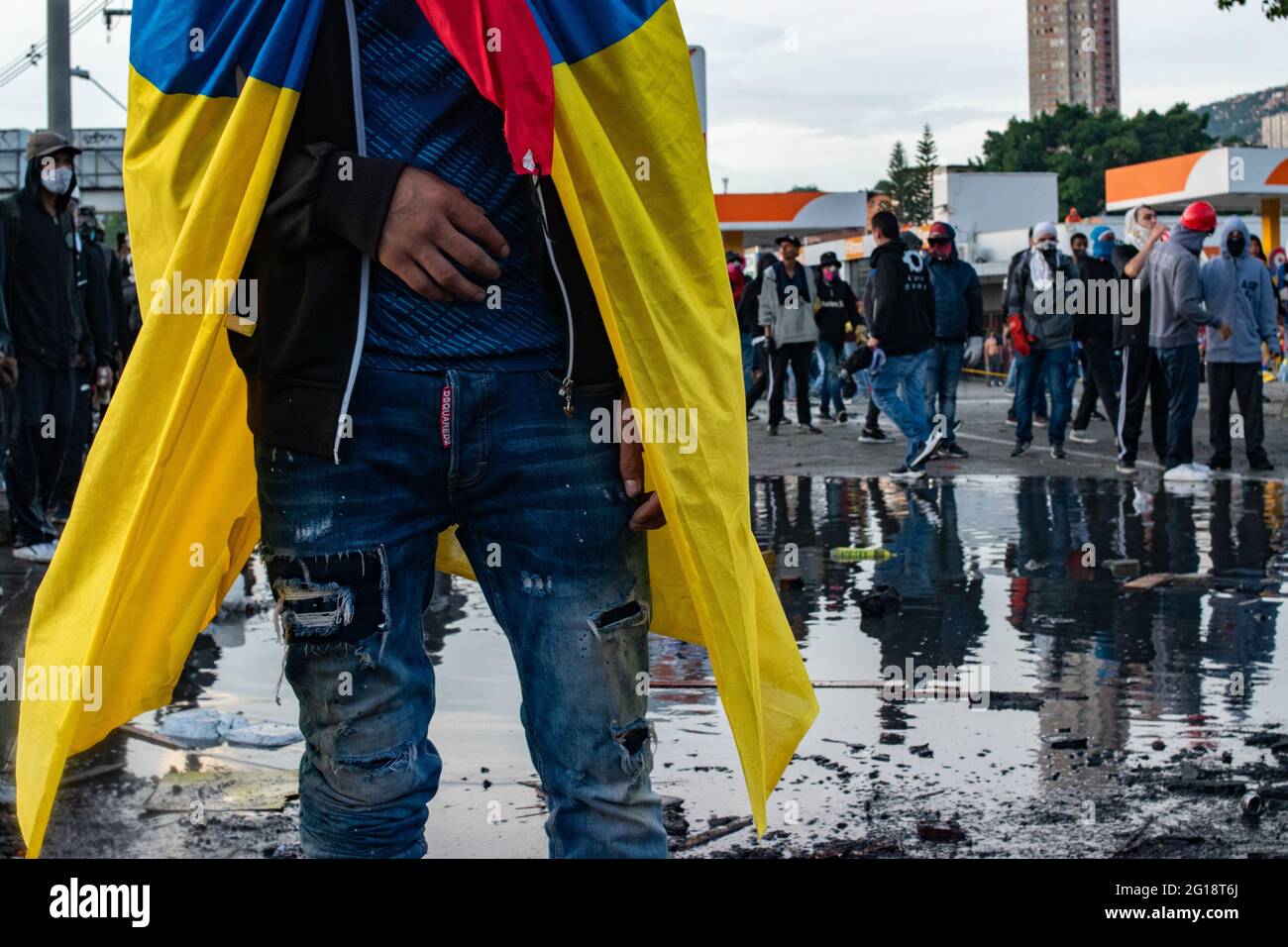 A member of the front line with a Colombian flag as clashes between demonstrators and Colombia's riot police (ESMAD) erupt in Medellín, Colombia after several weeks of anti-government protest against President Ivan Duque's tax and health reforms and unrest and abuse of authority cases that leave at least 70 dead according to NGOs on June 4, 2021. Stock Photo