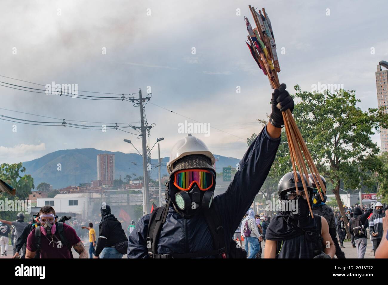 A demonstrator from the front line lifts firework crackers as clashes between demonstrators and Colombia's riot police (ESMAD) erupt in Medellín, Colombia after several weeks of anti-government protest against President Ivan Duque's tax and health reforms and unrest and abuse of authority cases that leave at least 70 dead according to NGOs on June 4, 2021. Stock Photo