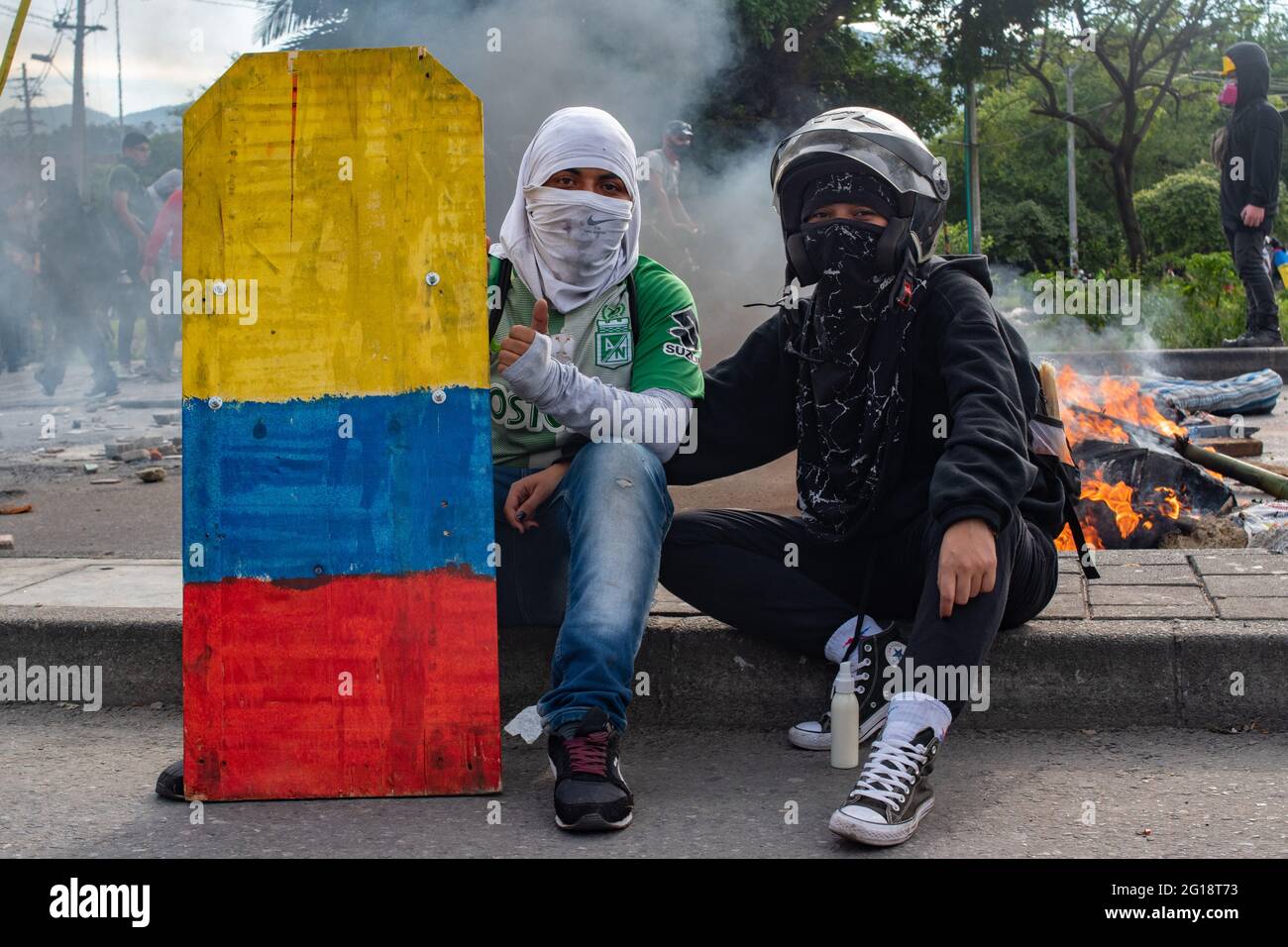 Members of the front line pose for a photo with a handcrafted shield with the Colombian national flag as clashes between demonstrators and Colombia's riot police (ESMAD) erupt in Medellín, Colombia after several weeks of anti-government protest against President Ivan Duque's tax and health reforms and unrest and abuse of authority cases that leave at least 70 dead according to NGOs on June 4, 2021. Stock Photo