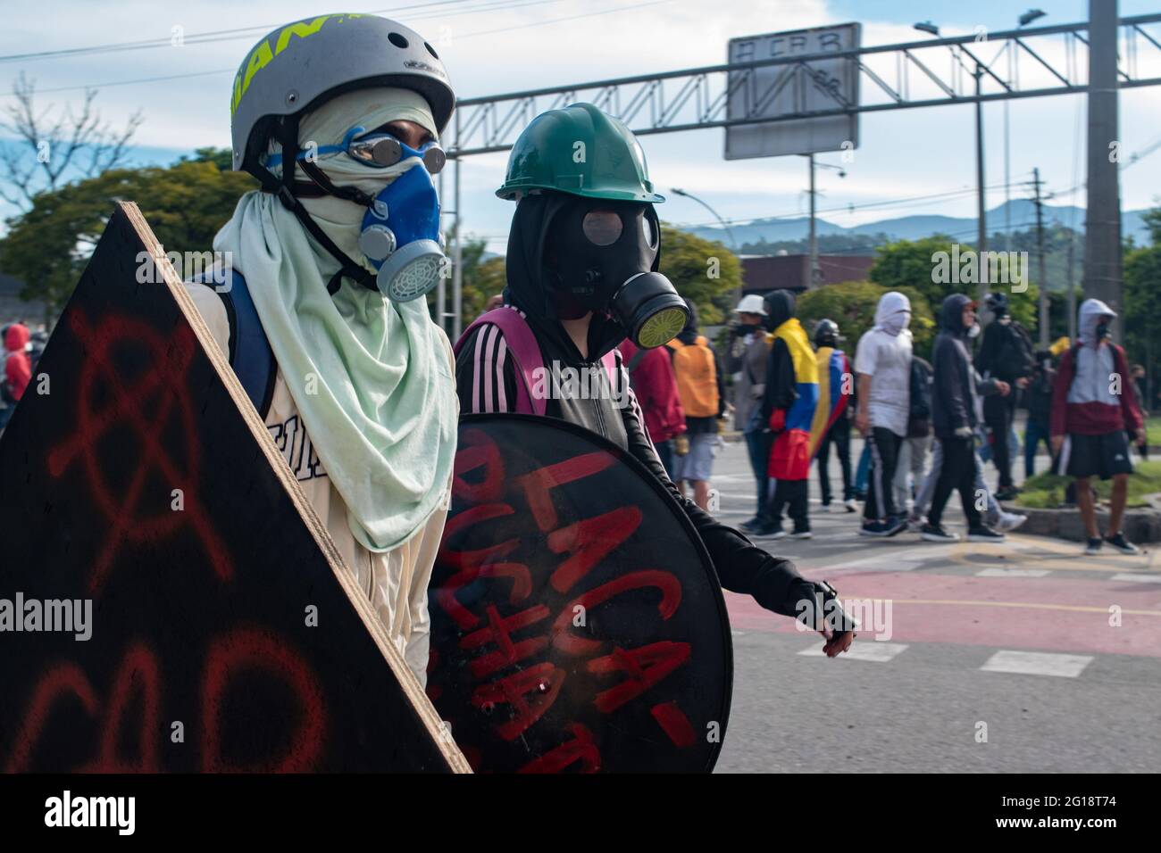 Members of the front line protect their identities with gas masks as clashes between demonstrators and Colombia's riot police (ESMAD) erupt in Medellín, Colombia after several weeks of anti-government protest against President Ivan Duque's tax and health reforms and unrest and abuse of authority cases that leave at least 70 dead according to NGOs on June 4, 2021. Stock Photo