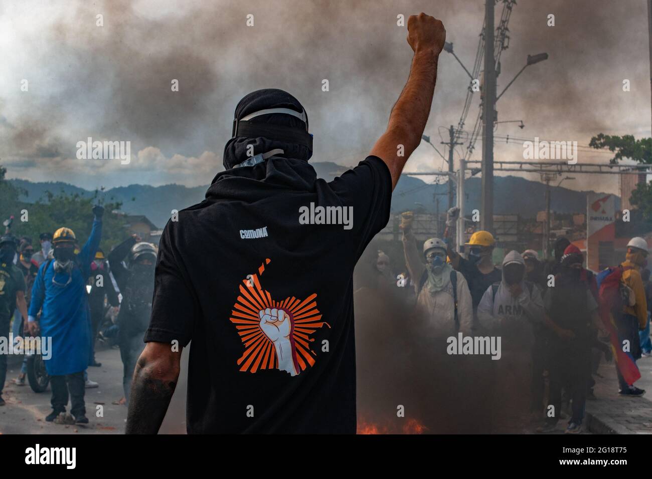 A member of the front line lifts its fist as he has a shirt with the geographical map of Colombia and a fist as clashes between demonstrators and Colombia's riot police (ESMAD) erupt in Medellín, Colombia after several weeks of anti-government protest against President Ivan Duque's tax and health reforms and unrest and abuse of authority cases that leave at least 70 dead according to NGOs on June 4, 2021. Stock Photo