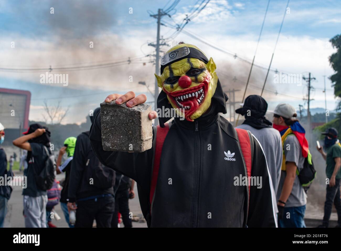 A member of the front line using a mask poses for a portrait holding a rock as clashes between demonstrators and Colombia's riot police (ESMAD) erupt in Medellín, Colombia after several weeks of anti-government protest against President Ivan Duque's tax and health reforms and unrest and abuse of authority cases that leave at least 70 dead according to NGOs on June 4, 2021. Stock Photo