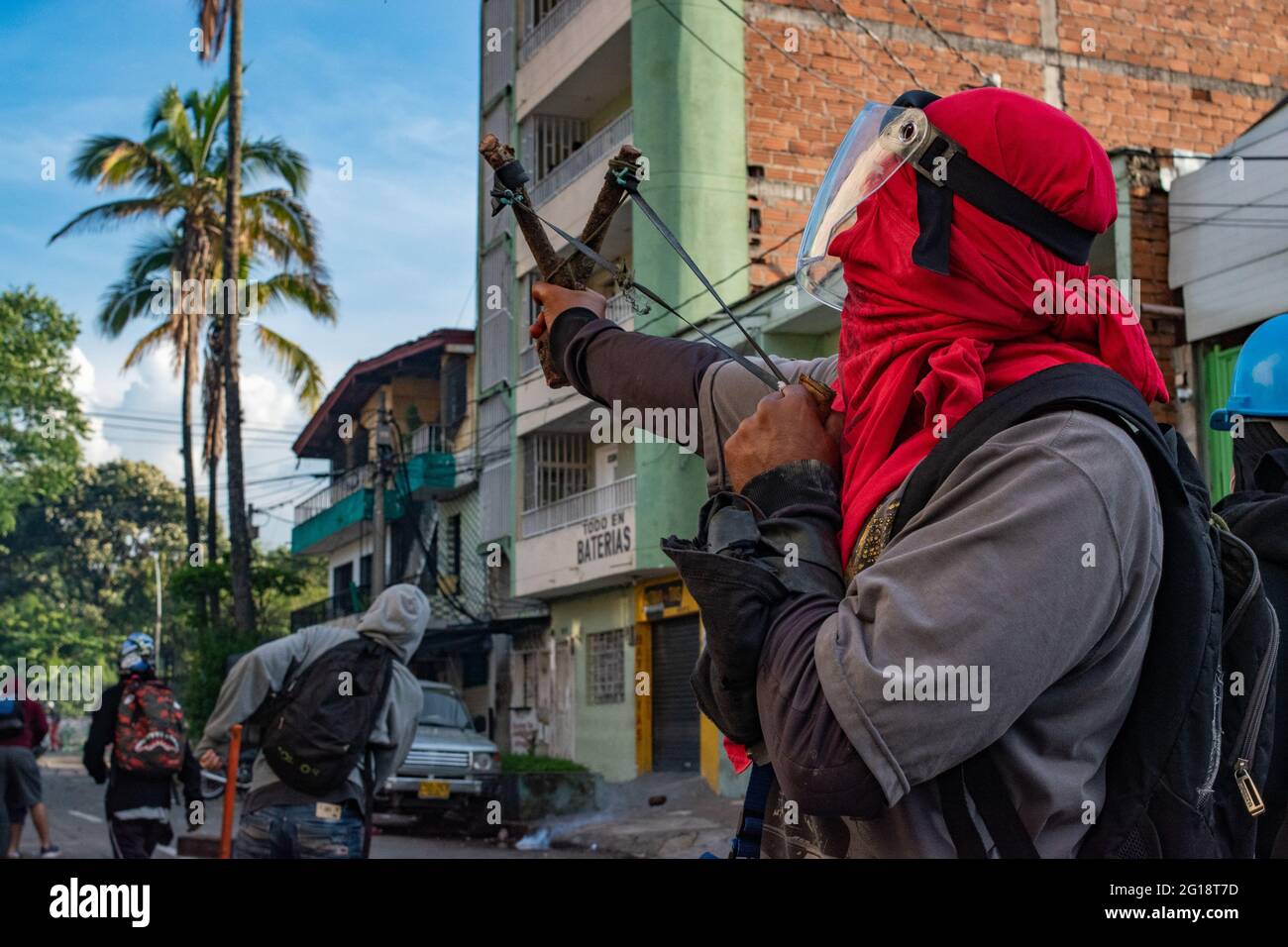 A demonstrator uses a slingshot as clashes between demonstrators and Colombia's riot police (ESMAD) erupt in Medellín, Colombia after several weeks of anti-government protest against President Ivan Duque's tax and health reforms and unrest and abuse of authority cases that leave at least 70 dead according to NGOs on June 4, 2021. Stock Photo