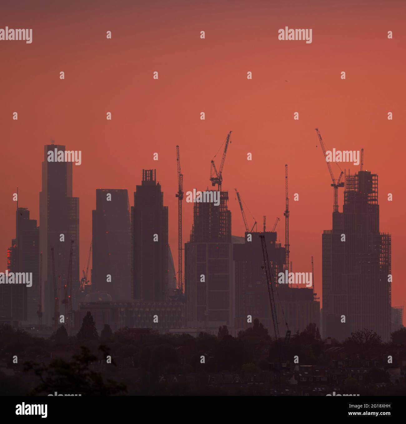 Wimbledon, London, UK. 6 June 2021. Skyscrapers in the centre of London silhouetted against an orange dawn sky. Credit: Malcolm Park/Alamy Live News Stock Photo