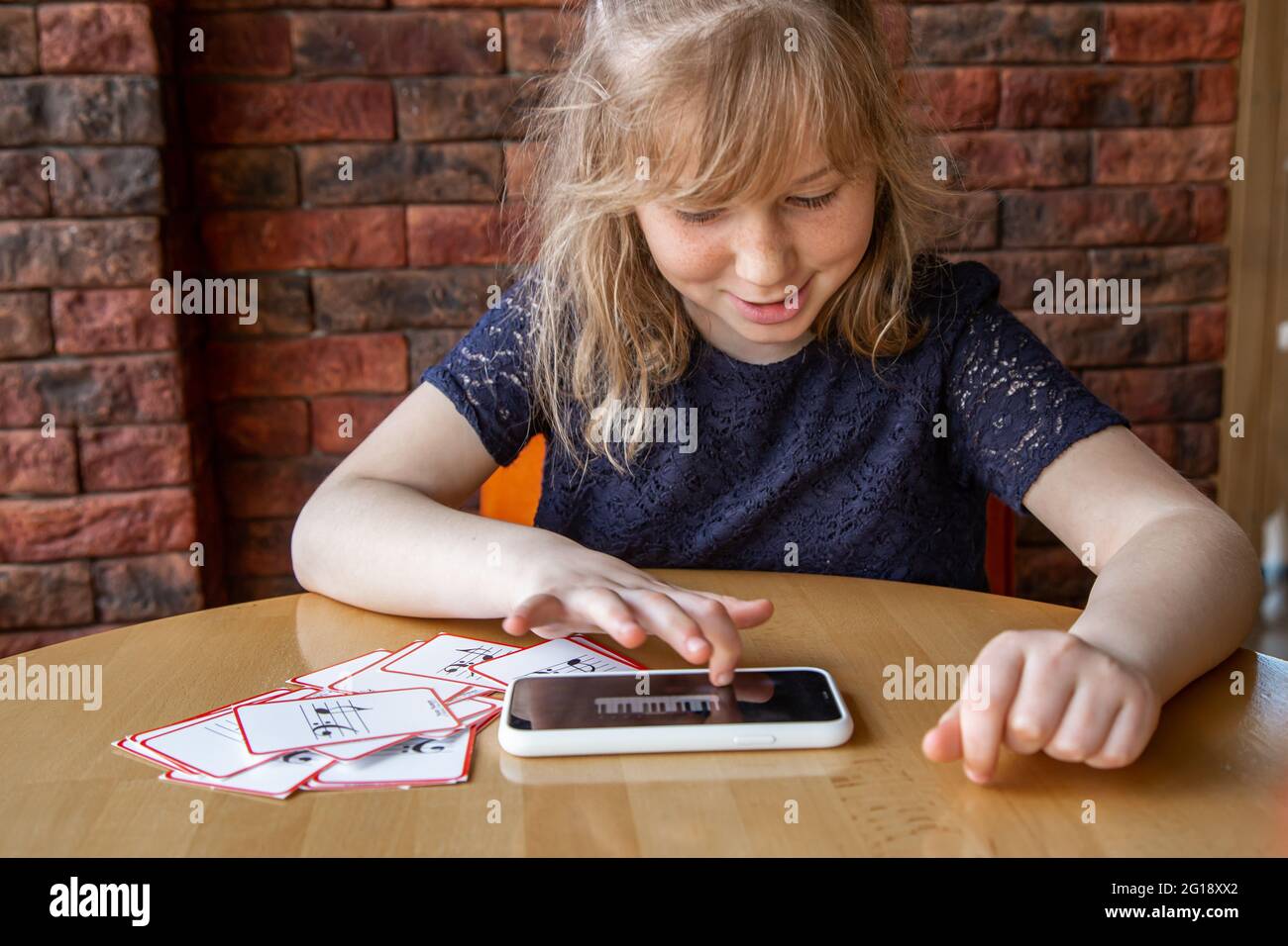 A little girl learns notes in a playful way, with the help of special musical cards. Stock Photo