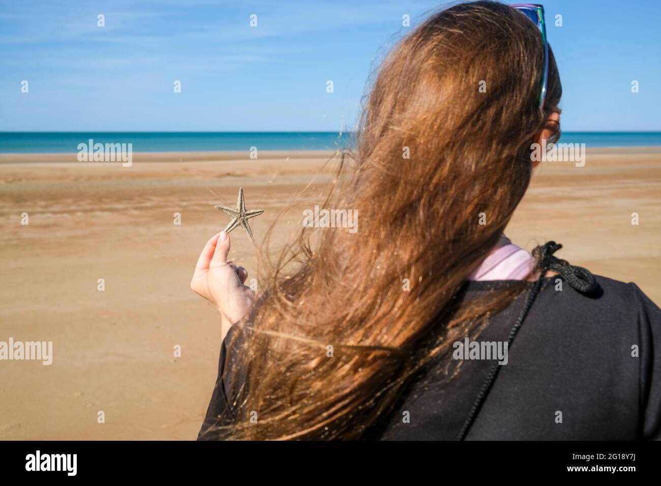Girl holding a starfish at the beach Stock Photo