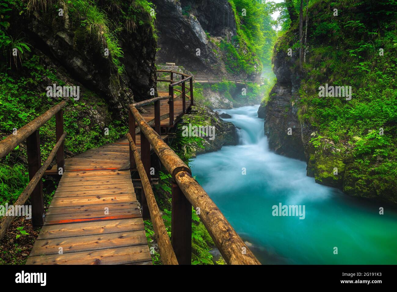 Narrow wooden footbridge in the misty Vintgar gorge. Beautiful scenery with mountain river in the deep gorge, Bled, Slovenia, Europe Stock Photo