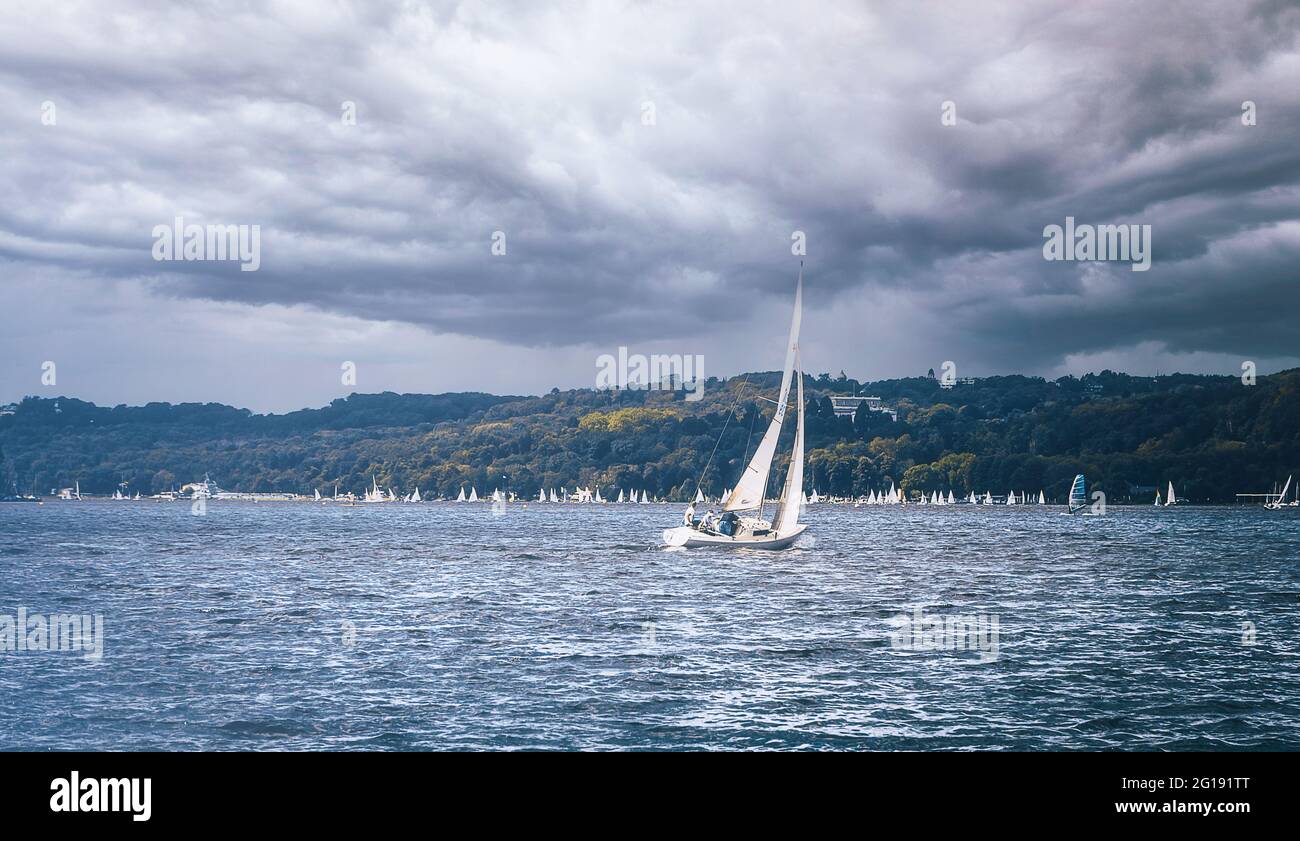 Seegelschiff bei schlechtem Wetter und rauhem Wellengang am Baldeneysee in Essen Werden im Sommer. Seegelboot in voller Fahrt am See bei Gewitter Wolk Stock Photo