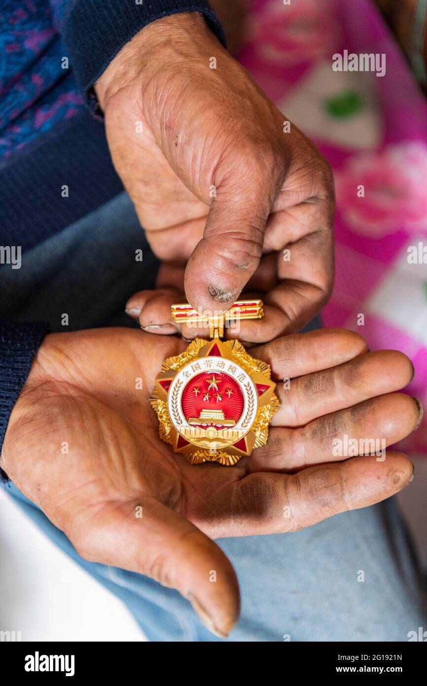 210606) -- YICHUN, June 6, 2021 (Xinhua) -- Zhang Yingshan shows the medal  of National Model Worker he was awarded at home in a forest farm  administered by Wumahe forestry bureau in