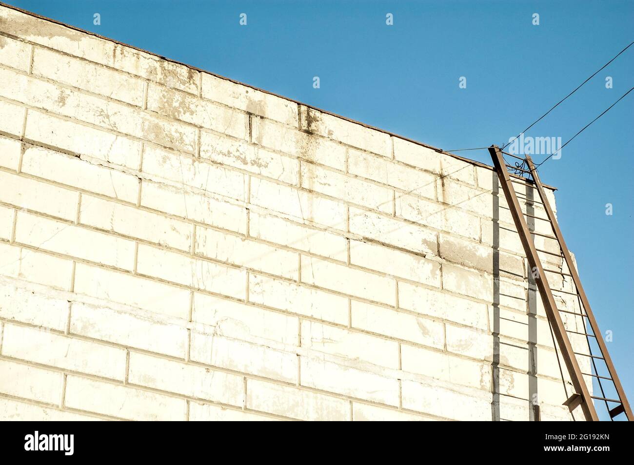 Modern warehouse building with an iron staircase casting shadow on te wahite wall Stock Photo