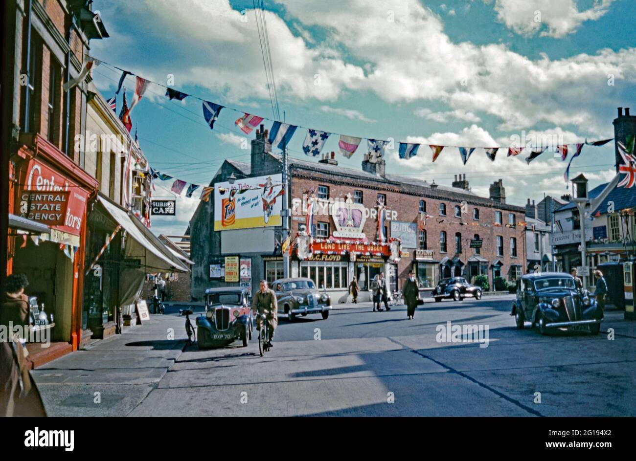 There is colourful bunting across the street, union flags flying and a large sign with a crown and the words ‘Long live the Queen’ in Surrey Street, Littlehampton, West Sussex, England, UK in 1953. This was for the coronation of Elizabeth II which took place on 2 June 1953 at Westminster Abbey, London. Littlehampton is a seaside town, lying on the English Channel on the eastern bank of the River Arun. This image is from an old amateur 35mm Kodak colour transparency – a vintage 1950s photograph. Stock Photo