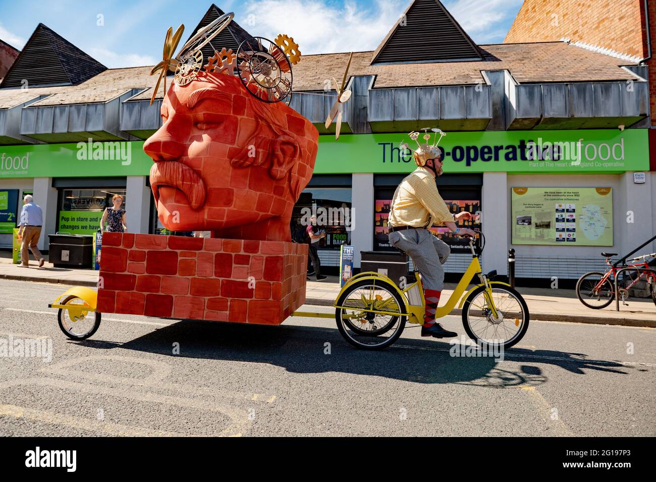 The launch day of Coventry City of Culture 2021,a man rides a tricycle with a bust of James Starley (bicycle industrialist) on the trailer.  there were vehicle parades around the city showcasing the motorcar and the bicycle history of the city. Performances accompanied the displays. Stock Photo
