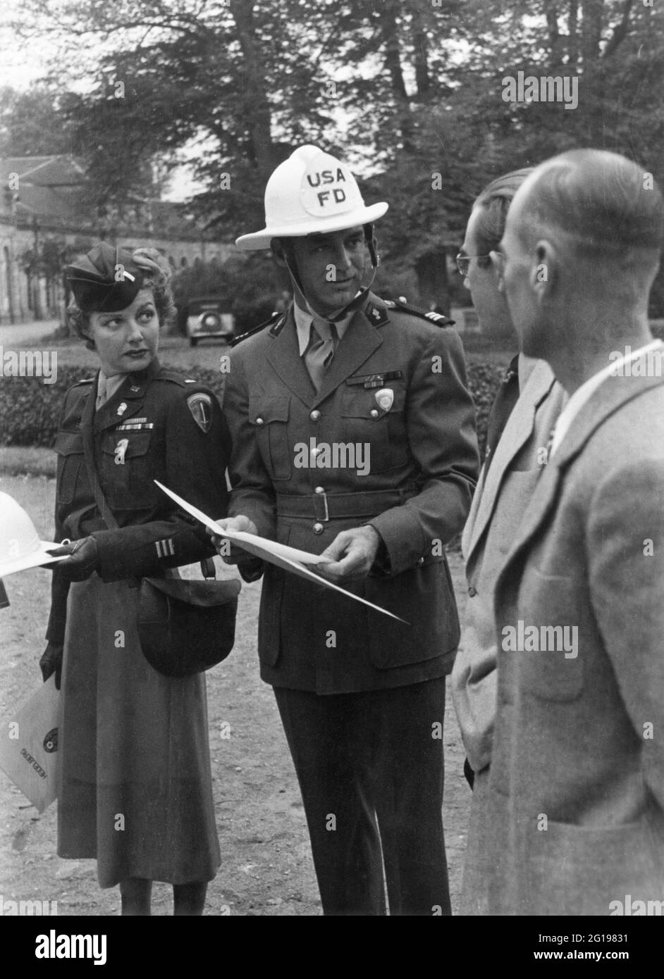 ANN SHERIDAN and CARY GRANT wearing US Firefighter Helmet on locationwith Two Men likely from USAFD in Germany during filming of I WAS A MALE WAR BRIDE 1949 director HOWARD HAWKS story Henri Rochard screenplay Charles Lederer Leonard Spigelgass and Hagar Wilde Twentieth Century Fox Stock Photo