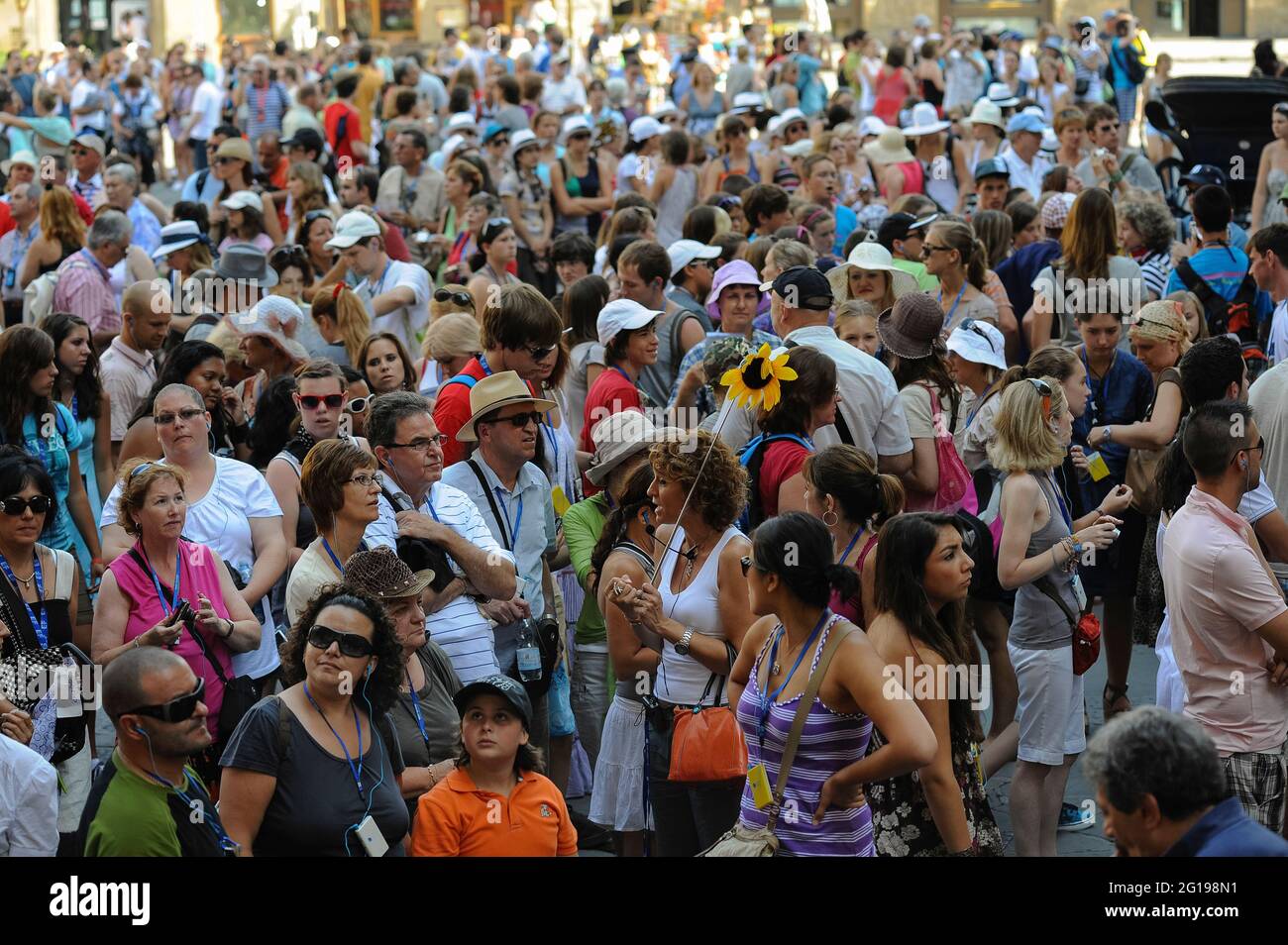 By mid-July, near the peak of the summer high season, Piazza della Signoria, the historic heart of Florence, Tuscany, Italy, is packed throughout the day with visitors from all over the world.  This image, captured from the Loggia dei Lanzi outdoor sculpture gallery, shows hundreds of people listening to tourist guides, taking photographs and marvelling at sights such as the Palazzo Vecchio, the city’s town hall and centre of civic power since it was founded in 1299. Stock Photo
