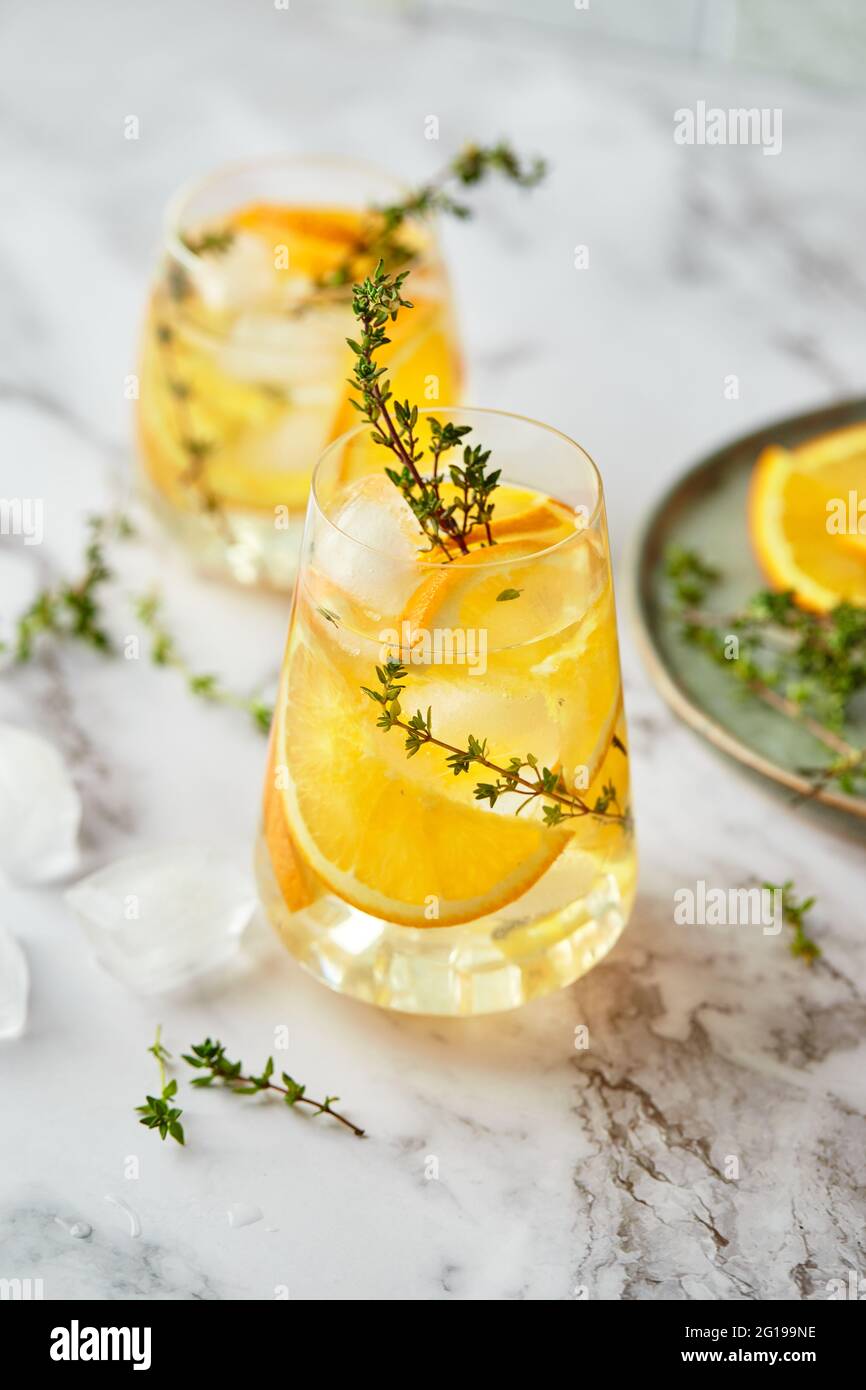 Refreshing cocktail with ice, orange and thyme. Refreshing summer homemade alcoholic or non-alcoholic cocktail or mocktail, or Detox infused flavored Stock Photo