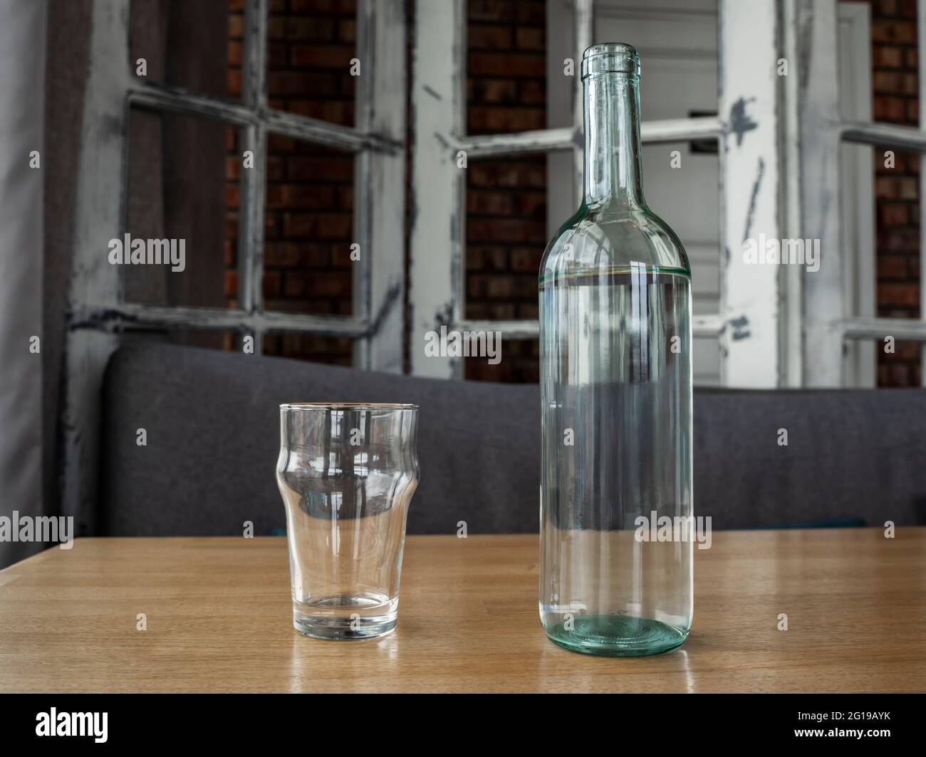 Clear glass bottle with water or white wine and two empty glass glasses. Stock Photo