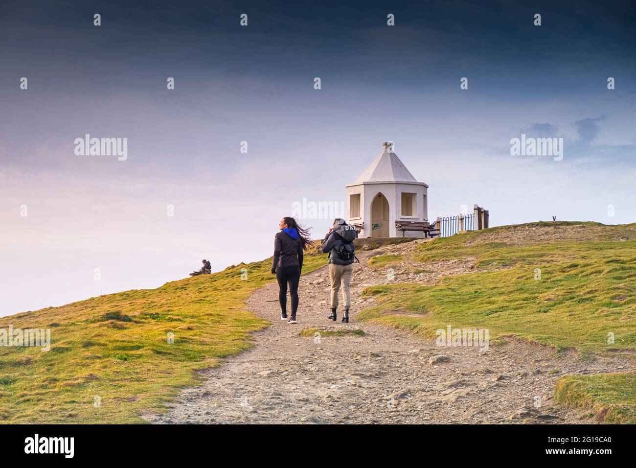 Two females walking up to the small white octagonal Old Coastguard Lookout Station on the top of Towan Head in Newquay in Cornwall. Stock Photo