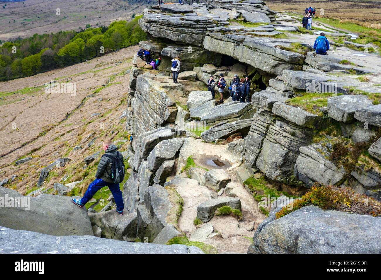 Crowds of walkers at Robin Hoods Cave, and Hope Valley seen from the popular gritstone cliff of Stanage Edge, Derbyshire, Peak District Stock Photo