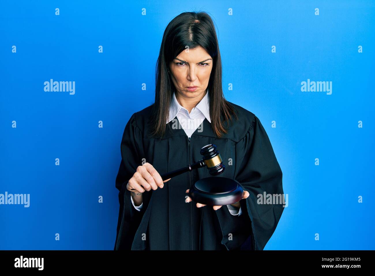 Young hispanic woman using gavel depressed and worry for distress, crying angry and afraid. sad