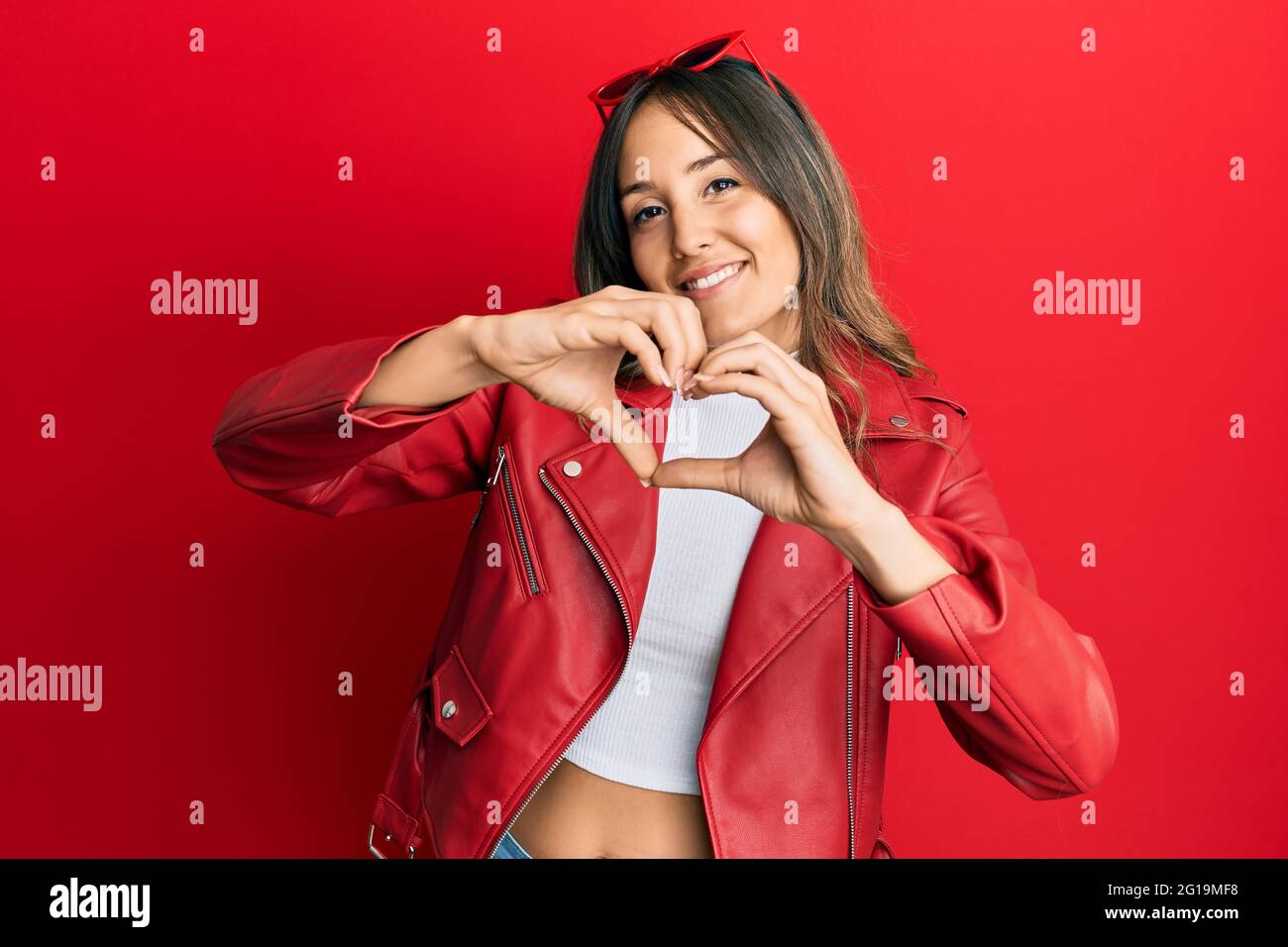 Young brunette woman wearing red leather jacket smiling in love doing ...