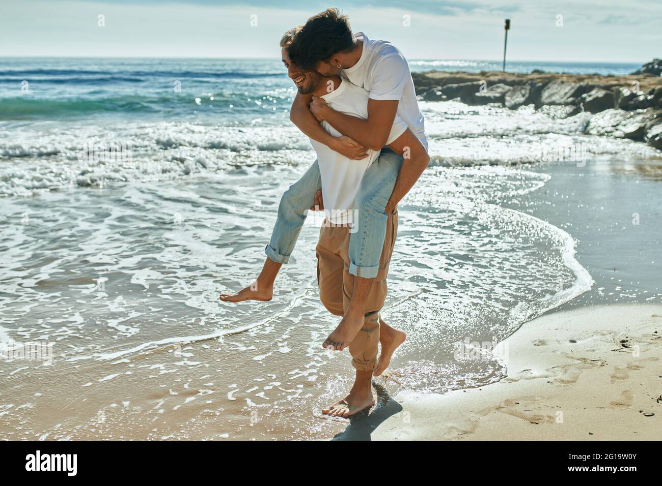 Lovely gay couple on piggyback ride at the beach Stock Photo - Alamy