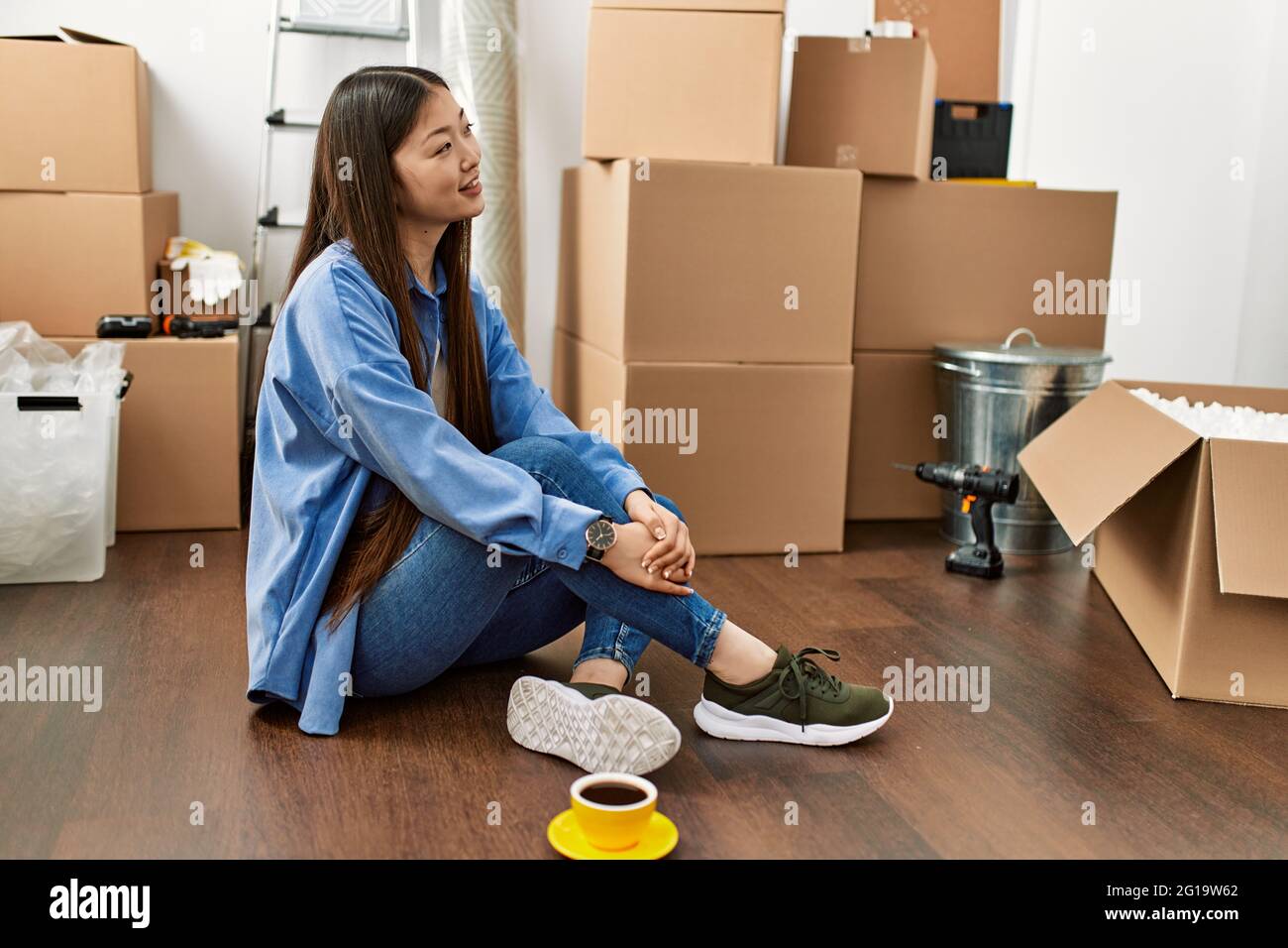 Young chinese girl smiling happy sitting on the floor at new home Stock ...