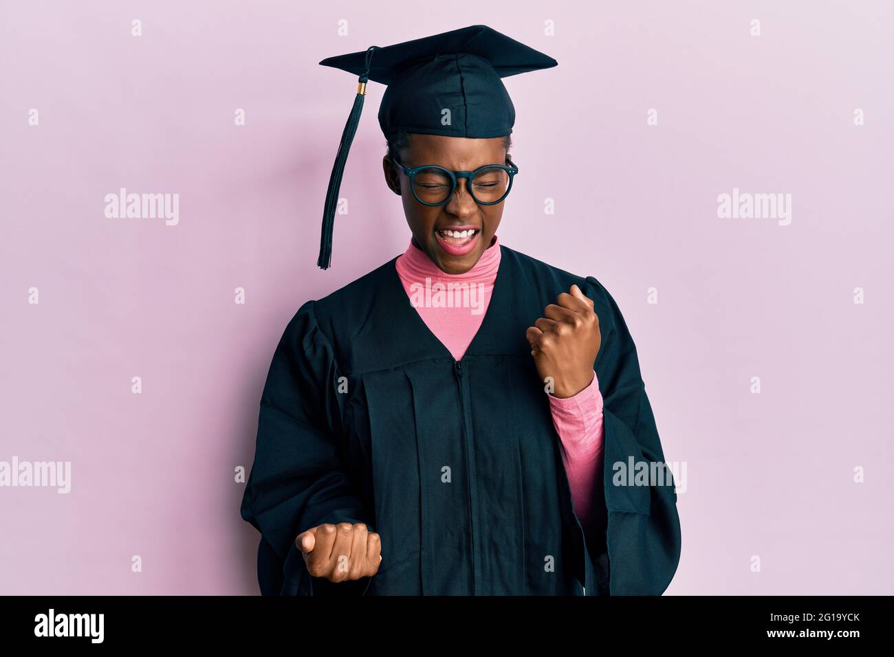 Young african american girl wearing graduation cap and ceremony robe celebrating surprised and amazed for success with arms raised and eyes closed. wi Stock Photo