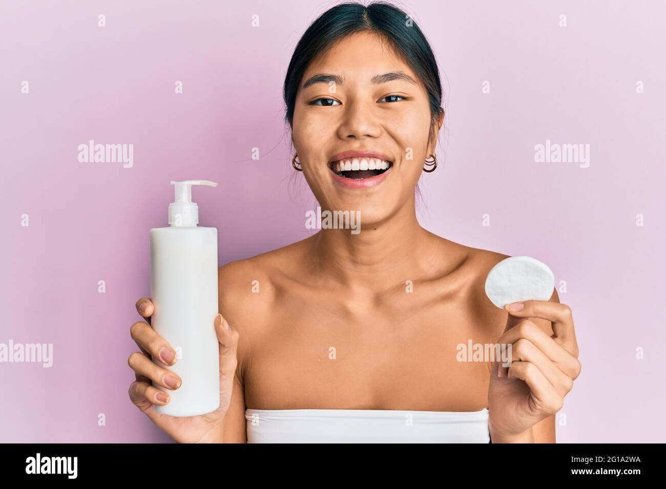 Young chinese woman wearing shower towel using clean lotion smiling and