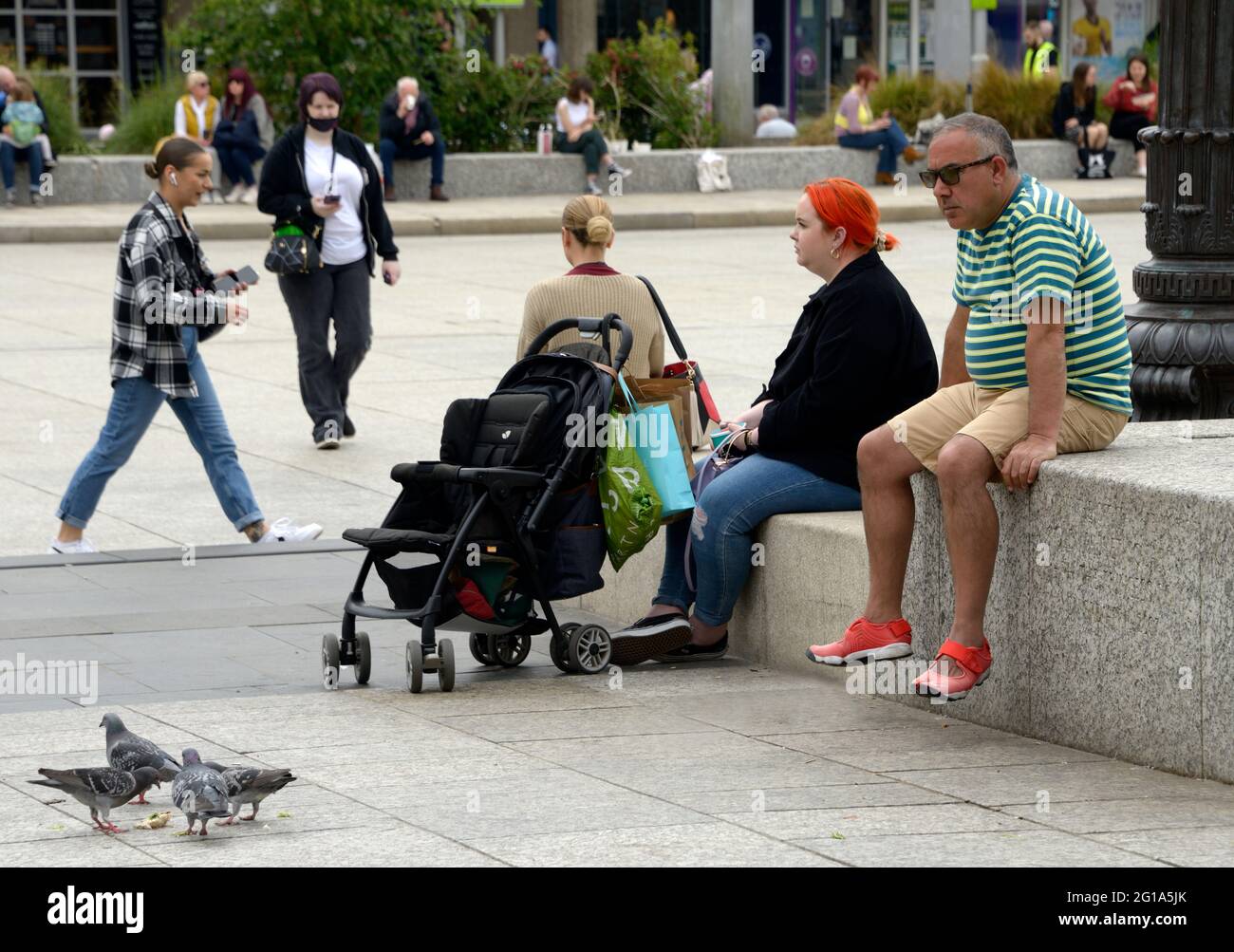 People passing time, sat in the City centre. Stock Photo