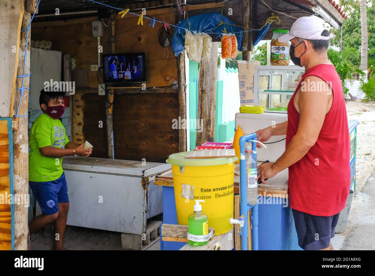Covid Pandemic: Small roadside shop in Yucatan Mexico. The clients and workers are wearing face masks and hand sanitizer is available . All small businesses take precautions while trying to stay open to survive Stock Photo
