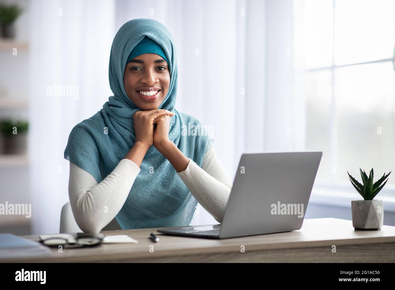Happy Smiling Black Muslim Lady In Hijab Sitting At Desk With Laptop ...