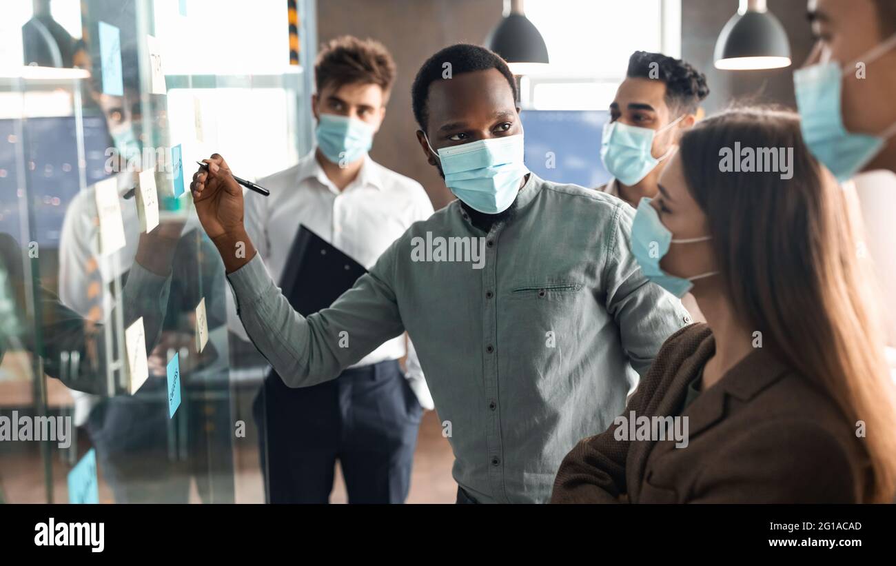 Workers in masks having meeting using sticky adhesive notes Stock Photo