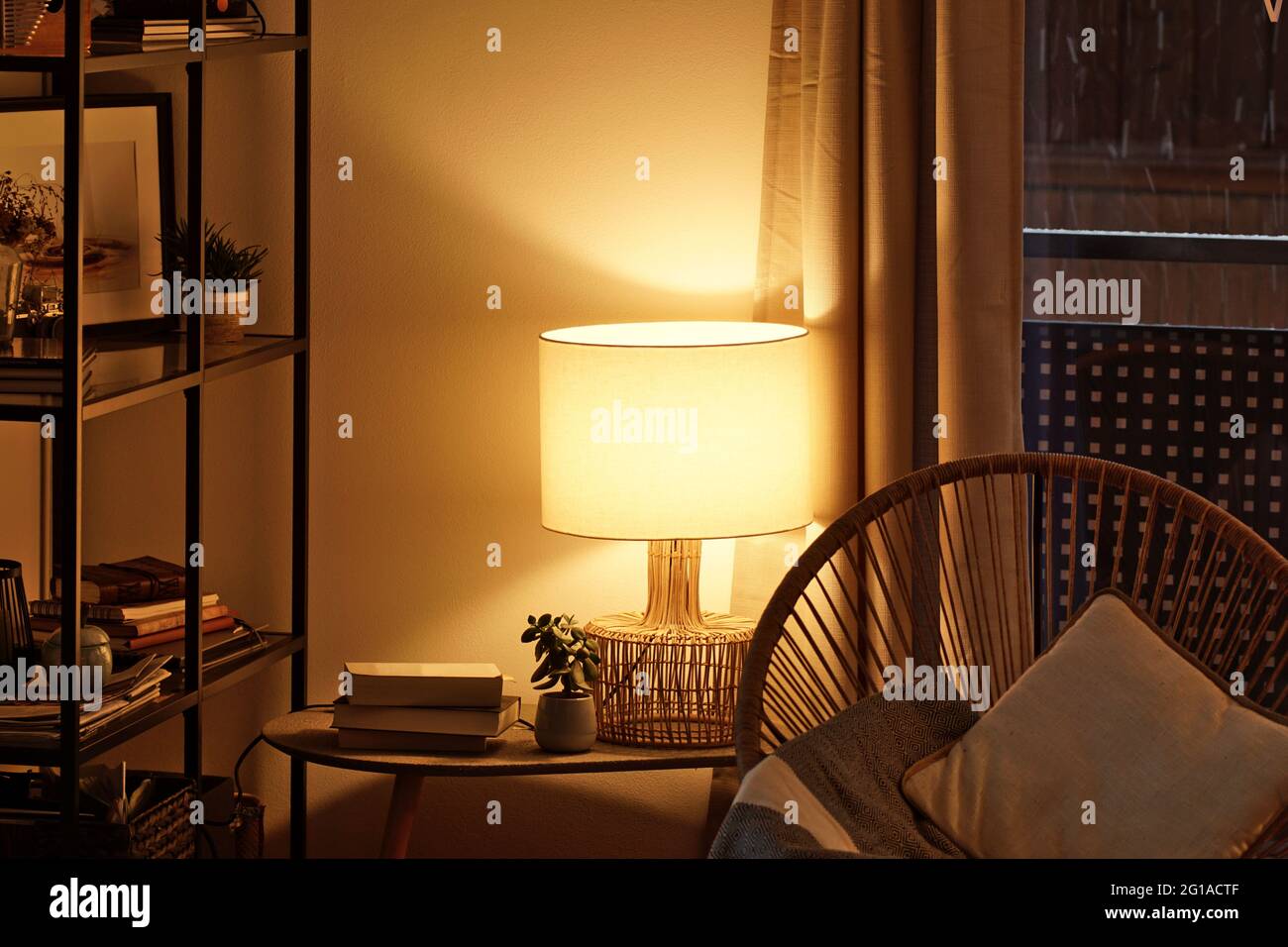 View of a cozy reader's corner with a table lamp spending warm light Stock Photo