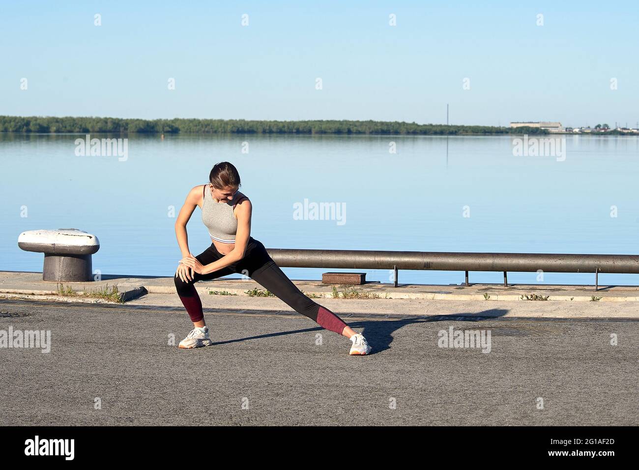 Focused fitness woman in activewear exercising with barbell during