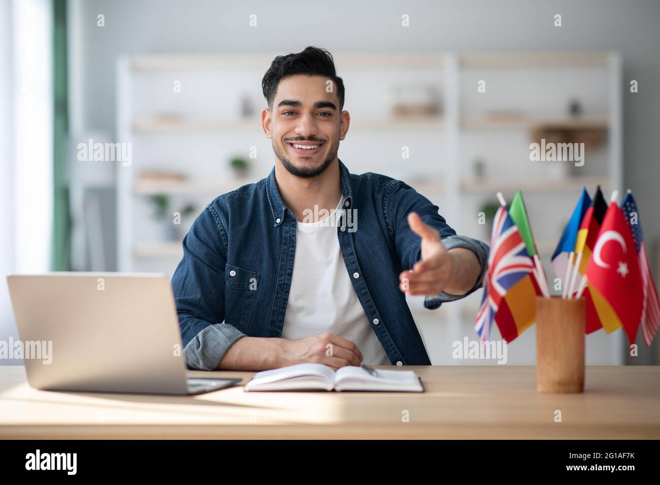 Cheerful arab guy foreign language teacher giving hand Stock Photo - Alamy