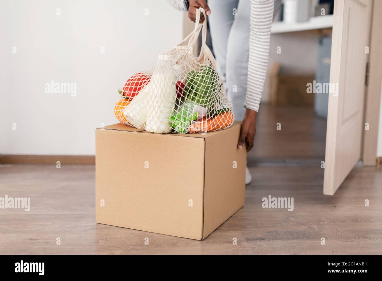 African Woman Carrying Delivered Grocery Shopping Bag And Box Indoors Stock Photo