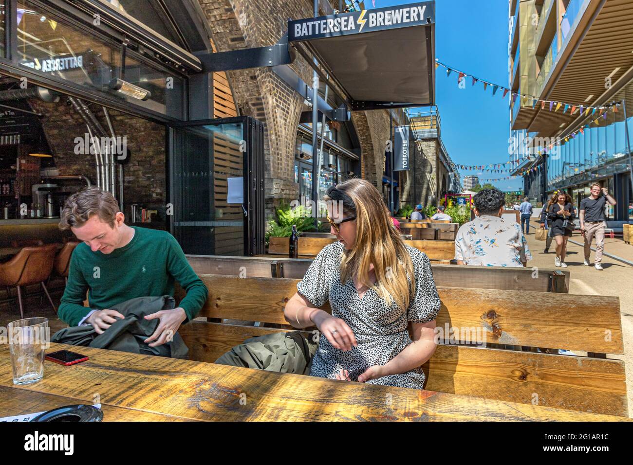 Customers sitting at a table at Battersea Brewery a micro brewery under the railway arches in Circus West Village at  Battersea Power Station,London Stock Photo