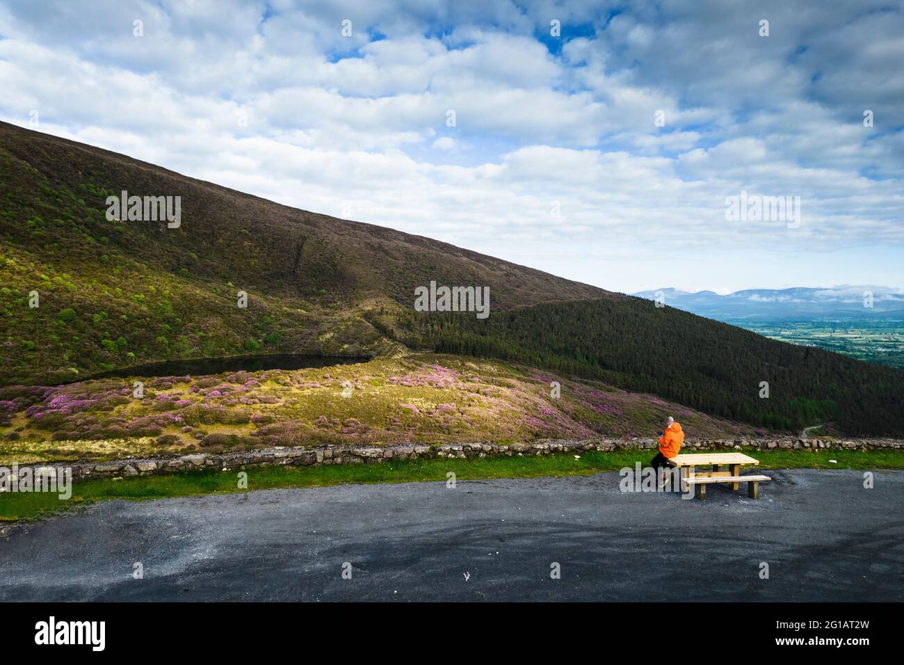 A man sits on a bench admiring the view near Bay Lough lake in Clogheen, county Tipperary in Ireland Stock Photo